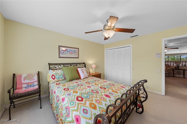 bedroom with light colored carpet, ceiling fan, and a closet