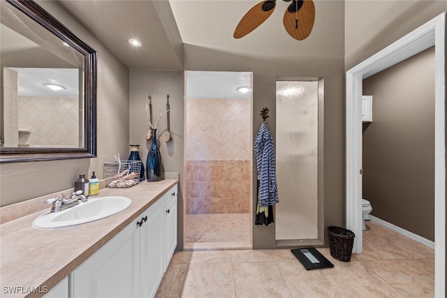 bathroom featuring tile patterned flooring, toilet, tiled shower, ceiling fan, and vanity