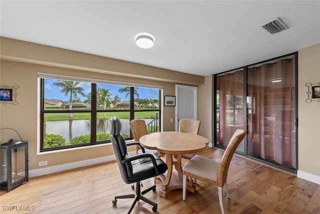 dining space with a water view and hardwood / wood-style flooring