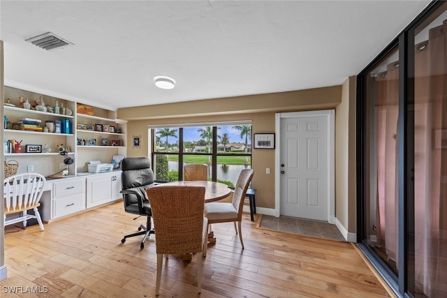 office space with built in desk and light hardwood / wood-style floors