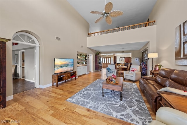 living room with high vaulted ceiling, ceiling fan, and light hardwood / wood-style floors