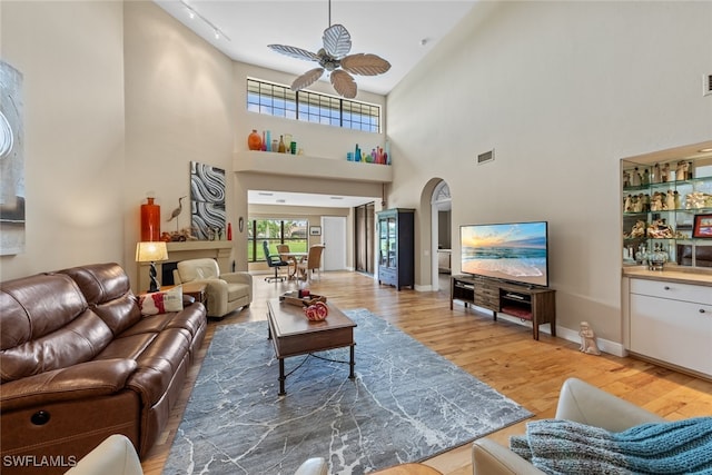 living room with ceiling fan, wood-type flooring, and a high ceiling