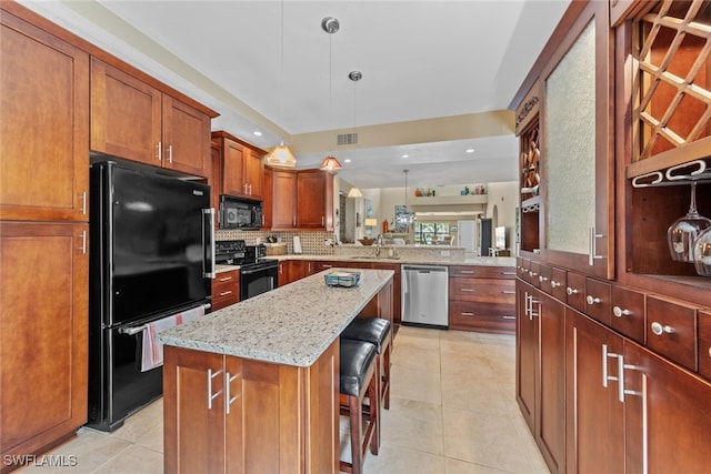 kitchen with decorative light fixtures, a kitchen breakfast bar, black appliances, light stone counters, and a kitchen island