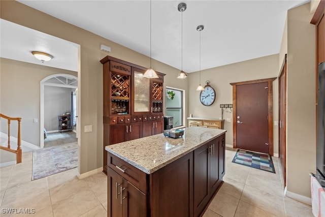 kitchen featuring light tile patterned floors, a kitchen island, decorative light fixtures, and light stone countertops