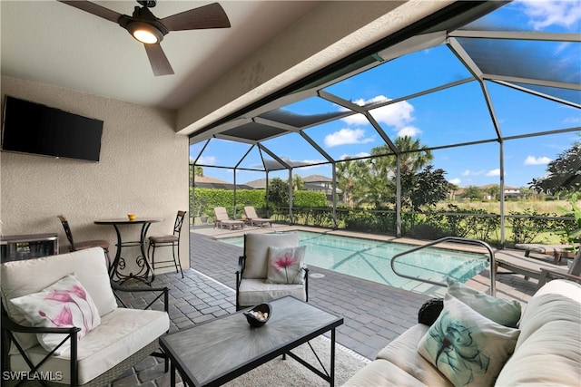 view of pool featuring glass enclosure, ceiling fan, a patio, and an outdoor living space