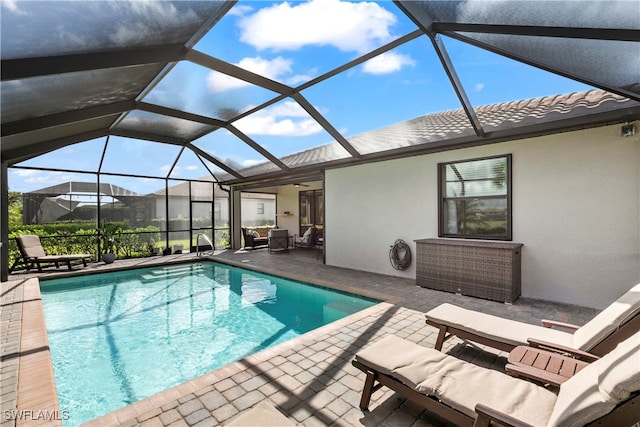 view of pool with glass enclosure and a patio