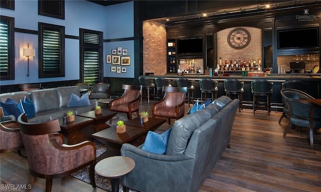 interior space featuring bar area, hardwood / wood-style floors, a towering ceiling, and brick wall