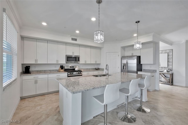 kitchen featuring pendant lighting, a center island with sink, sink, appliances with stainless steel finishes, and white cabinetry