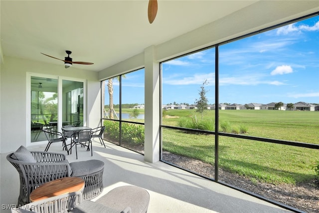 sunroom featuring ceiling fan and a water view