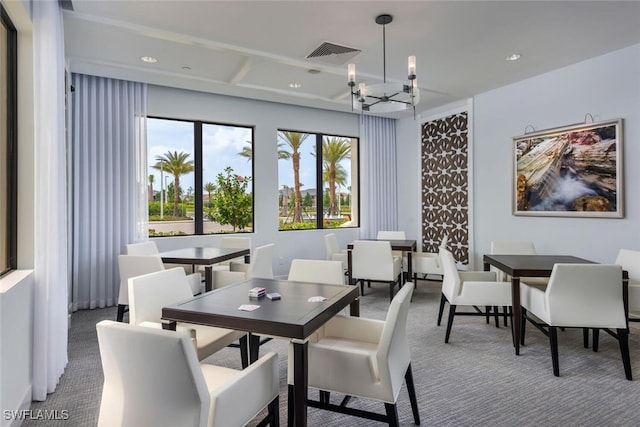 dining room with a healthy amount of sunlight, dark carpet, and a notable chandelier