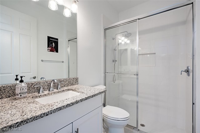 bathroom featuring a shower with door, vanity, and toilet