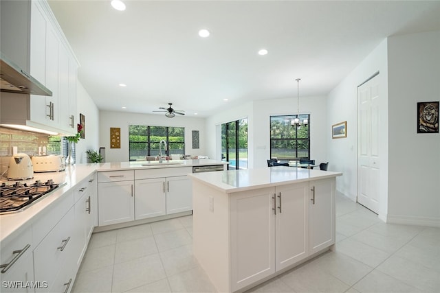 kitchen featuring stainless steel gas cooktop, white cabinetry, kitchen peninsula, ceiling fan, and extractor fan