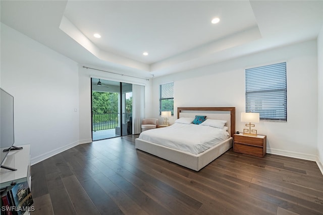 bedroom with a raised ceiling, dark hardwood / wood-style flooring, and access to outside