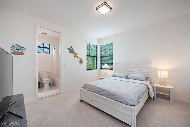 bedroom featuring connected bathroom and light carpet