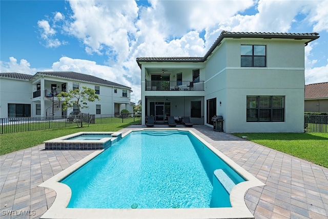 rear view of property with a balcony, a lawn, a patio, and a pool with hot tub