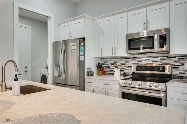 kitchen featuring white cabinets, light stone counters, sink, and appliances with stainless steel finishes