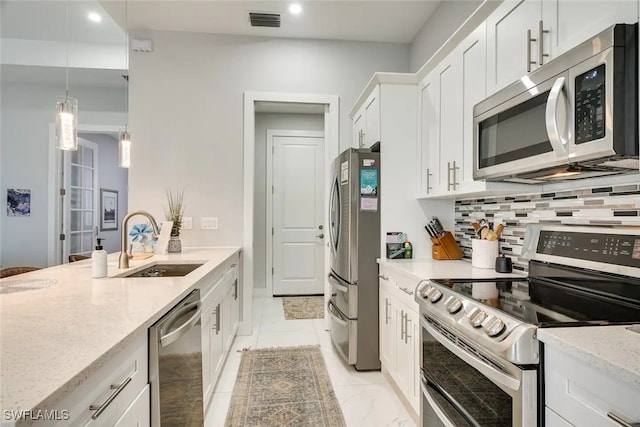 kitchen featuring white cabinetry, sink, stainless steel appliances, light stone counters, and pendant lighting