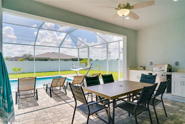 view of patio with glass enclosure, a fenced in pool, an outdoor kitchen, ceiling fan, and area for grilling