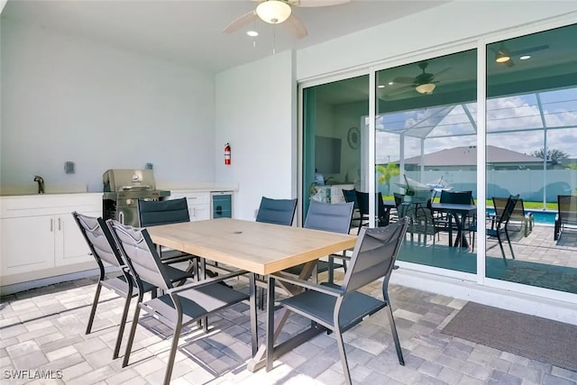 interior space featuring glass enclosure, ceiling fan, sink, beverage cooler, and grilling area