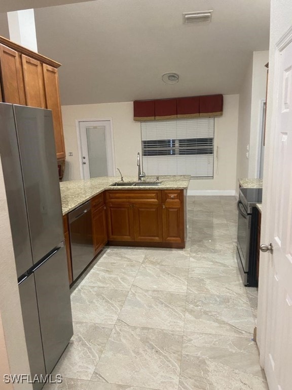 kitchen with kitchen peninsula, sink, light stone counters, and stainless steel appliances