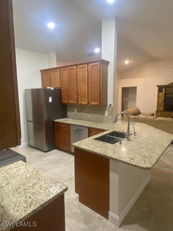 kitchen with stainless steel appliances, decorative backsplash, sink, kitchen peninsula, and vaulted ceiling