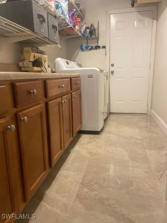 clothes washing area with cabinets and washing machine and clothes dryer