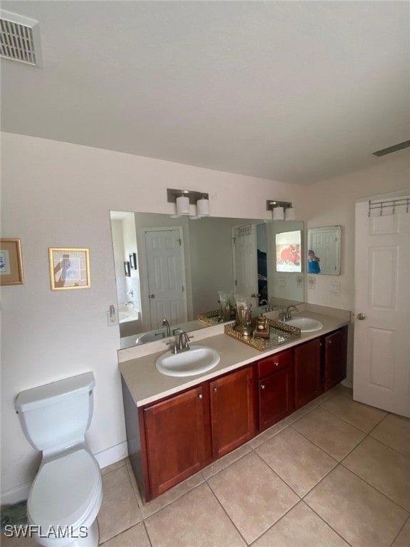 bathroom with tile patterned floors, toilet, vanity, and a tub to relax in