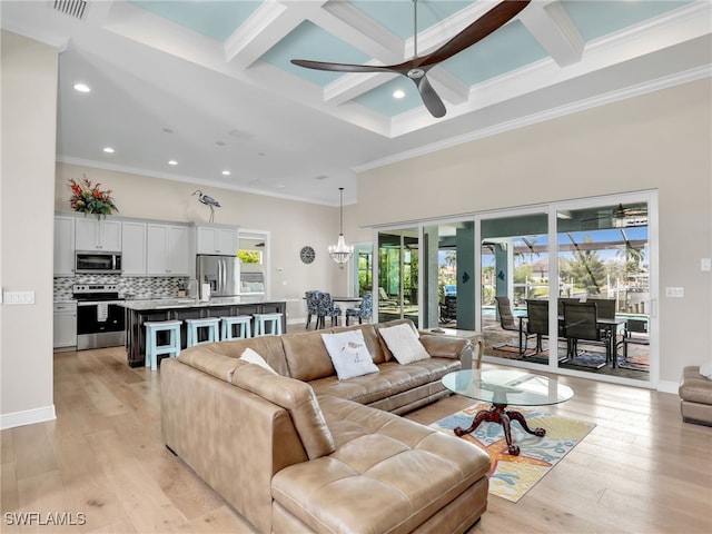 living room featuring ceiling fan with notable chandelier, beamed ceiling, light hardwood / wood-style flooring, crown molding, and coffered ceiling