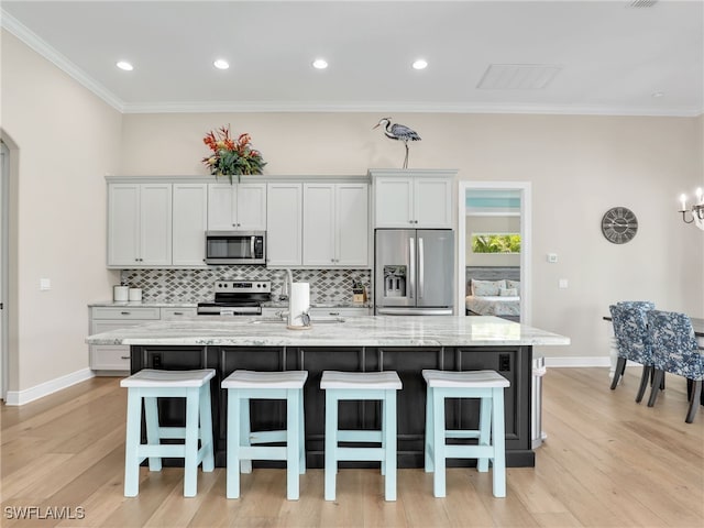 kitchen featuring a spacious island, white cabinetry, appliances with stainless steel finishes, and a breakfast bar