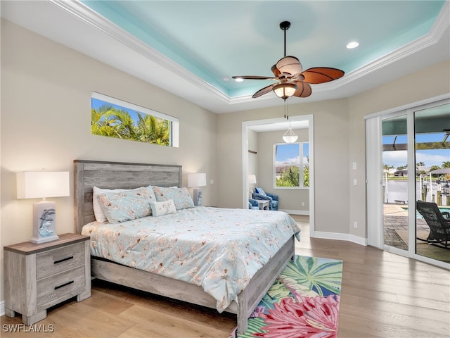 bedroom with ornamental molding, light hardwood / wood-style flooring, access to outside, ceiling fan, and a tray ceiling