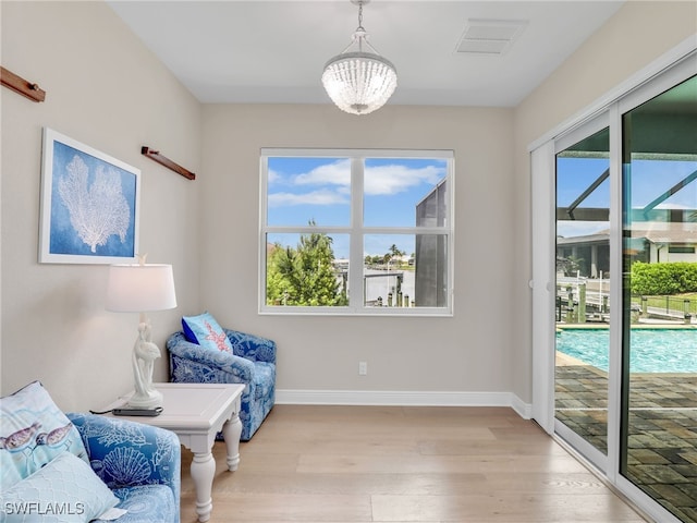 sitting room with light hardwood / wood-style floors, a notable chandelier, and plenty of natural light