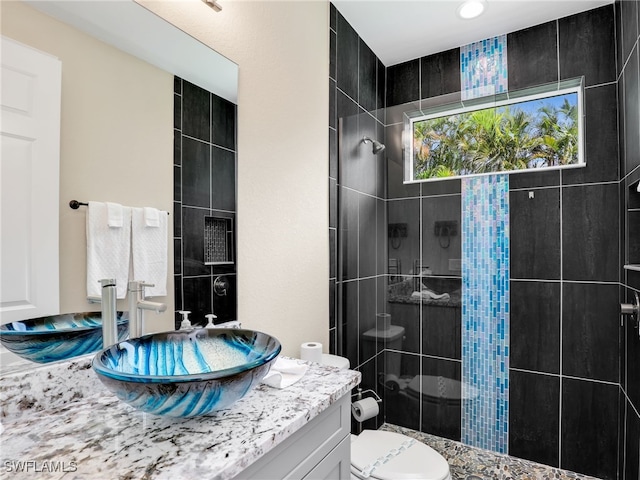 bathroom featuring vanity, toilet, and a tile shower