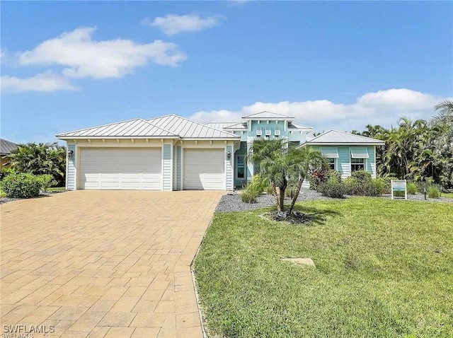 view of front of house with a front lawn, a standing seam roof, metal roof, decorative driveway, and an attached garage