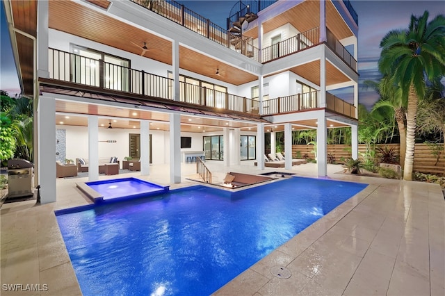 rear view of house featuring outdoor lounge area, a patio, a balcony, and a pool with hot tub