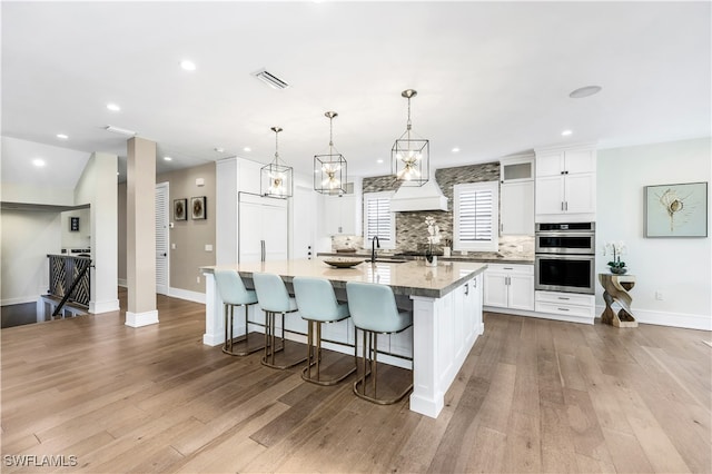 kitchen with pendant lighting, a breakfast bar, appliances with stainless steel finishes, a large island, and white cabinetry