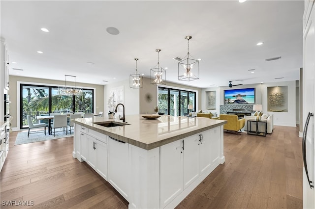 kitchen featuring pendant lighting, white cabinetry, sink, and a kitchen island with sink