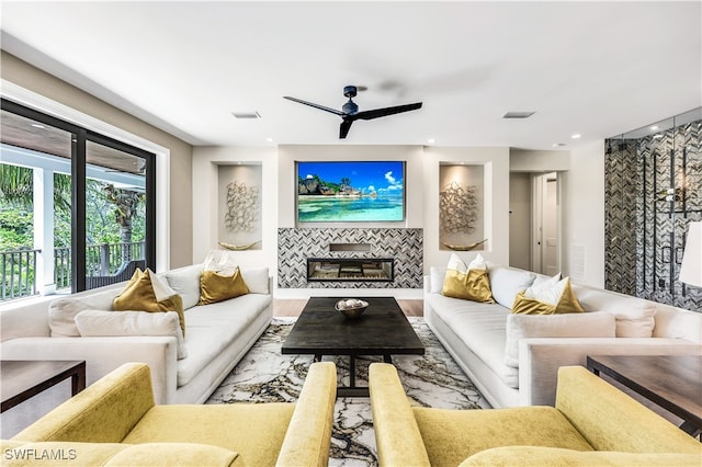 living room featuring a tile fireplace, ceiling fan, and wood-type flooring