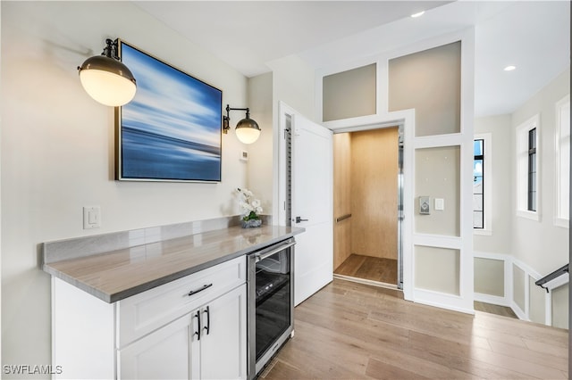 kitchen featuring light hardwood / wood-style floors, white cabinetry, and wine cooler