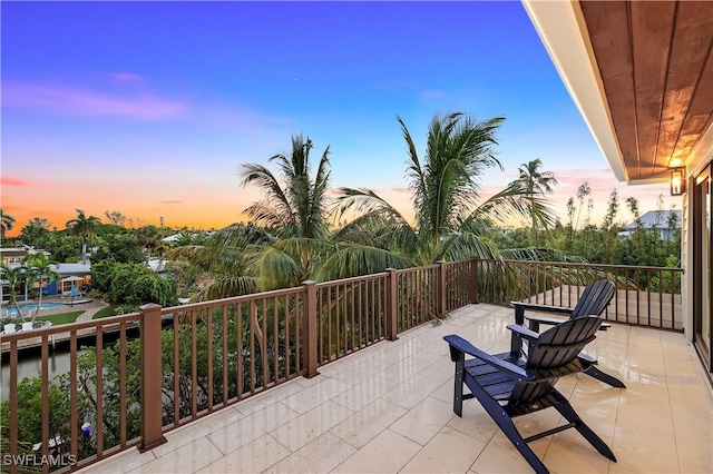 patio terrace at dusk featuring a balcony