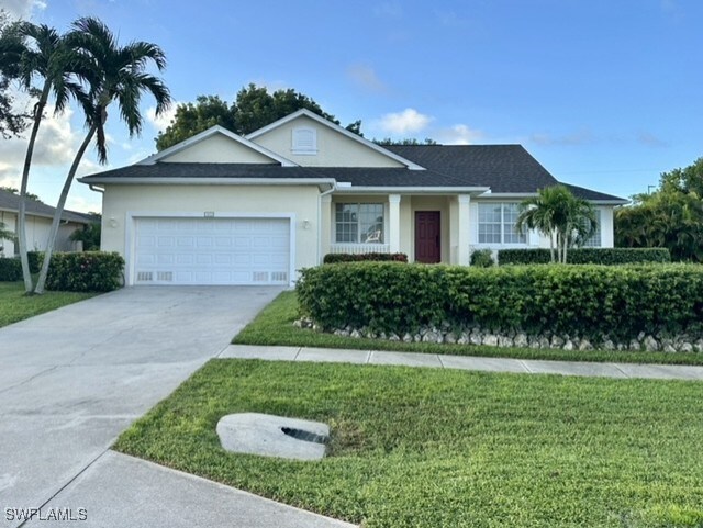 ranch-style home with a garage and a front lawn