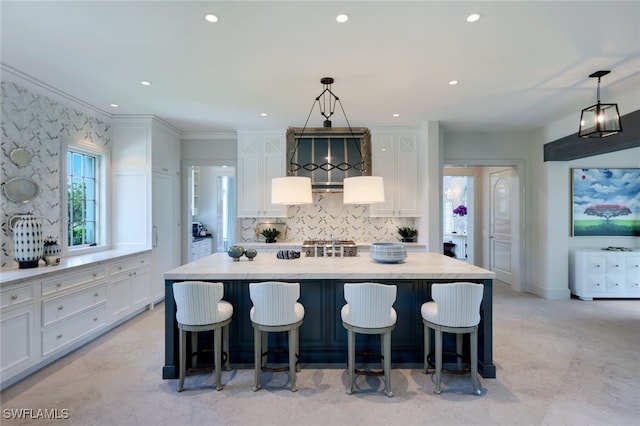 kitchen with a kitchen island with sink, white cabinets, and pendant lighting