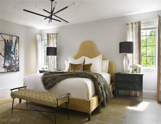 bedroom with light wood-type flooring and ceiling fan with notable chandelier