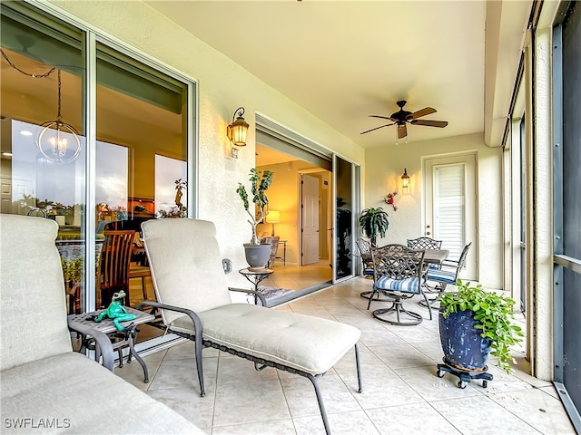 sunroom / solarium featuring ceiling fan with notable chandelier