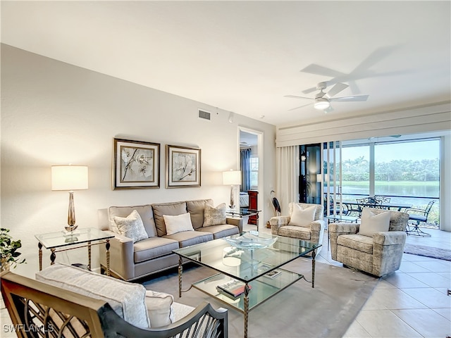 tiled living room featuring ceiling fan and a water view