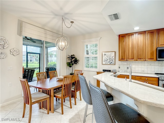 tiled dining space featuring ceiling fan with notable chandelier and plenty of natural light