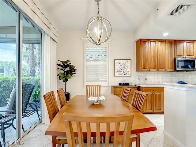 tiled dining room with lofted ceiling and a chandelier