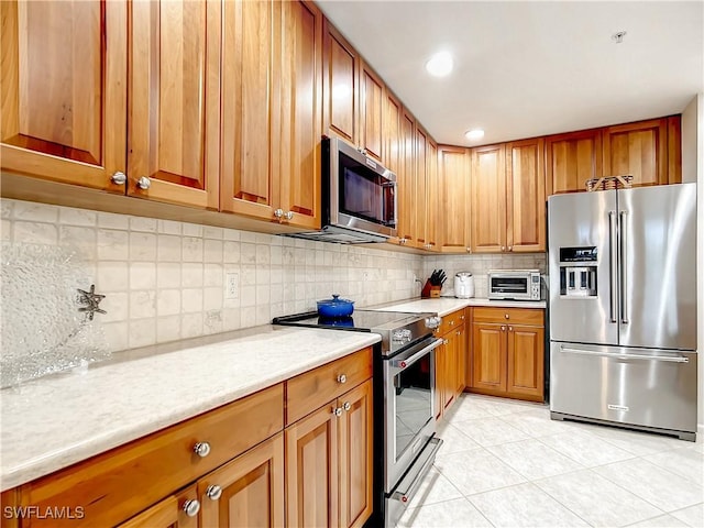 kitchen featuring tasteful backsplash, light tile patterned floors, stainless steel appliances, and light stone countertops