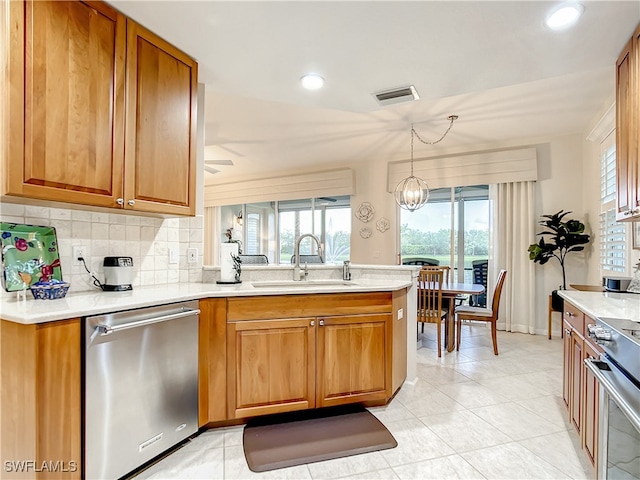 kitchen with tasteful backsplash, decorative light fixtures, kitchen peninsula, sink, and appliances with stainless steel finishes