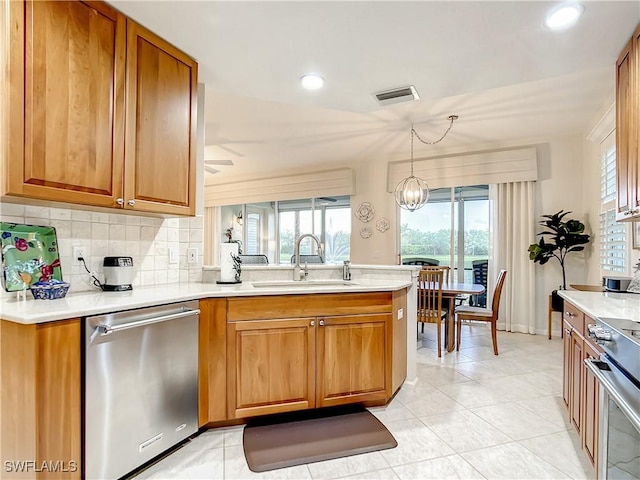 kitchen with sink, tasteful backsplash, hanging light fixtures, kitchen peninsula, and stainless steel appliances