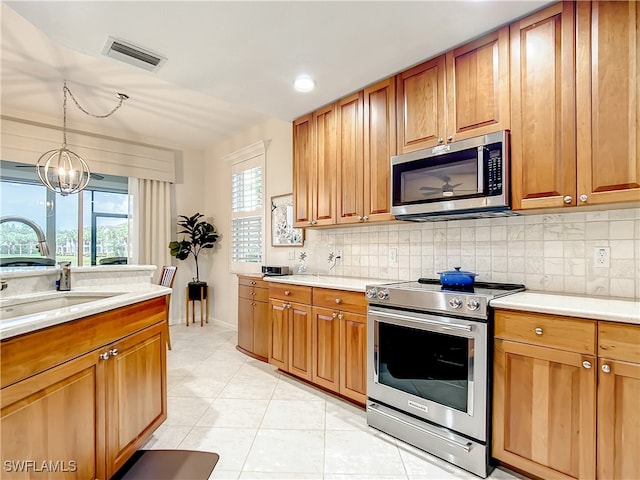 kitchen with appliances with stainless steel finishes, hanging light fixtures, a notable chandelier, and a healthy amount of sunlight